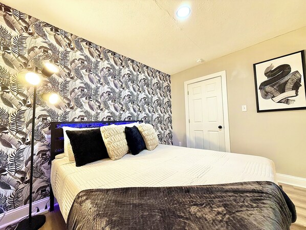 A bedroom with a bed, a floor lamp, a door, and a framed picture on the wall. - 5 Miles To Cedar Point By Sports Force Kalahari (Sandusky)