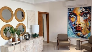A modern living room with a fireplace, a large abstract painting, and a wooden coffee table. - PF Hotel (Puerto Plata)