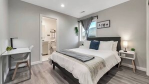 A modern bedroom with a large bed, bedside tables, a desk, and a view of the bathroom. - Spacious 6Bd/5Bath Willow Glen San Jose (San Jose)