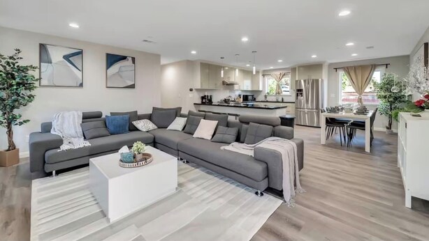 A modern living room with a grey sectional sofa, a white coffee table, and a dining area with a white table and chairs. - Spacious 6Bd/5Bath Willow Glen San Jose (San Jose)