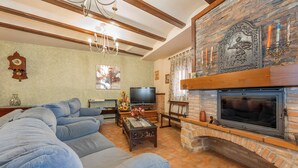 A living room with a stone fireplace, a television, and a large sofa.