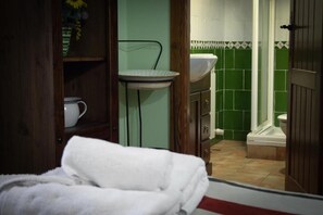 A bathroom with a green tiled wall, a white sink, and a wooden door.