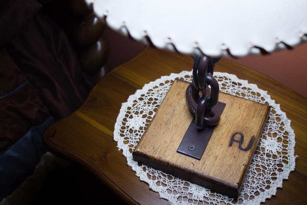 Una mesa de madera con un objeto metálico encima, un encaje blanco y la letra 'AU' en el lateral.
