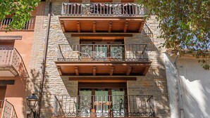 A multi-story building with a wooden balcony, stone facade, and a green sign indicating a restaurant.