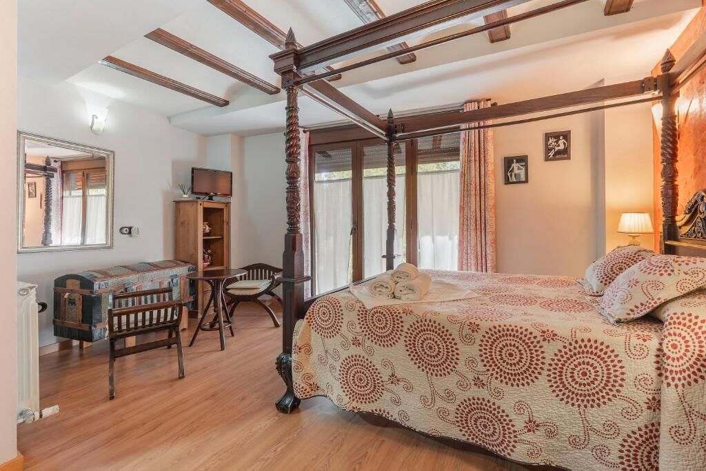 Een slaapkamer met een hemelbed, houten meubels en een televisie in een hoek.