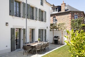 A patio with a dining table and chairs, a barbecue grill, and a small tree. - Villa Mariella - Parking Privé (Dinard)