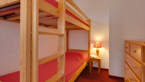 A bunk bed room with a wooden dresser and a small table with a lamp. - Studio Cosy Près des Pistes!  Local à Skis (Les Deux Alpes (Isère))