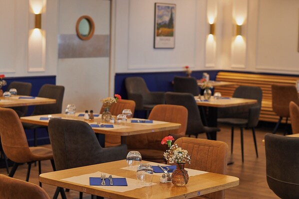 A restaurant with tables set for dining, chairs, and a vase with flowers on the table.