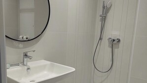 A modern bathroom with a white sink, a mirror, a shower, and a towel. - Les Trois Voiles (Port-Saint-Louis-du-Rhône)