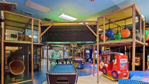 Ein Indoor-Spielbereich mit Billardtisch, Klettergerüsten und Spielautomaten.