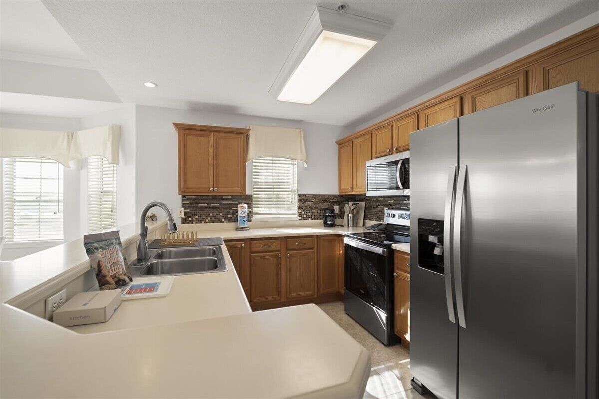 A modern kitchen with wooden cabinets, a stainless steel refrigerator, and a built-in oven.