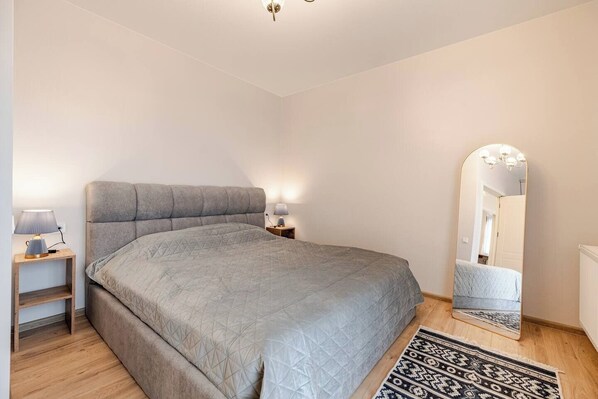 A bedroom with a large bed, bedside tables with lamps, a mirror, and a patterned rug. - Spacious City-View Home in Tbilisi Terrace & BBQ (Tbilisi)