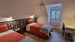 A bedroom with two beds, a desk, a window, and a sloped ceiling. - "En Chemin" (LE FAOUET)