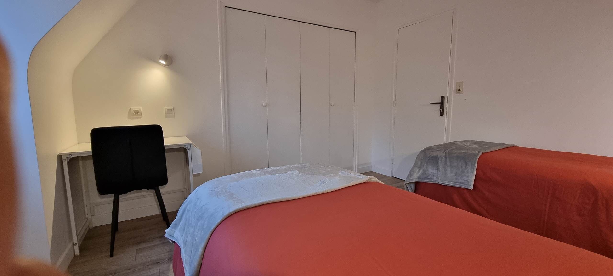 A room with two beds, a desk, and a chair.