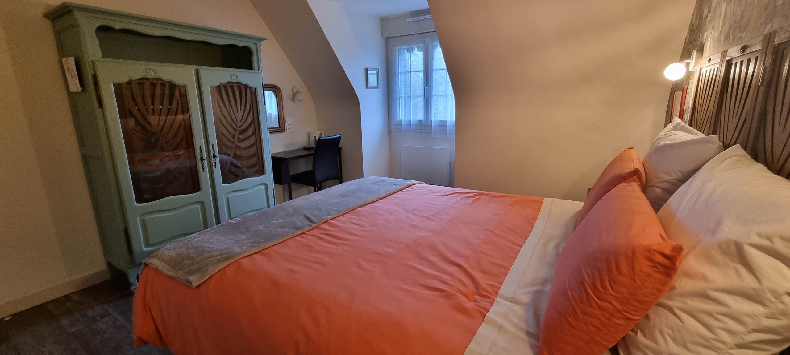 A bedroom with a bed, a wardrobe, and a desk.