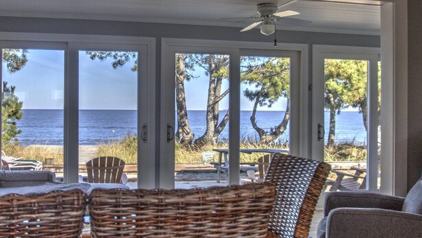 Una habitación con vista al mar, muebles de mimbre y un ventilador de techo.