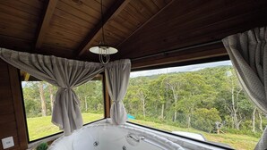 Una habitació amb un finestral gran, un sostre de fusta i una banyera.
