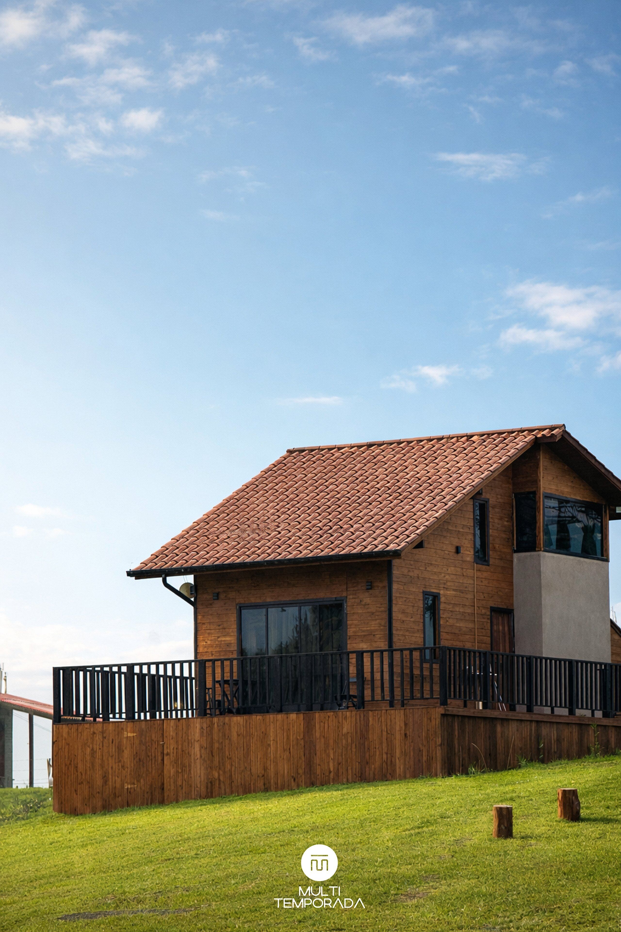Ein modernes Haus mit Ziegeldach, großen Fenstern und einem Holzzaun.