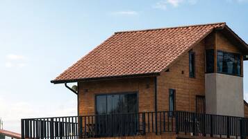 Ein modernes Haus mit Ziegeldach, großen Fenstern und einem Holzzaun.
