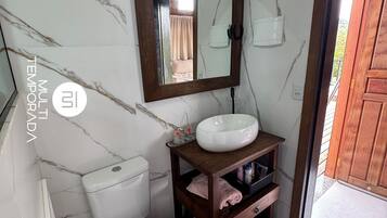 A bathroom with a toilet, a sink, a mirror, and a wooden cabinet.