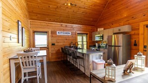 Ein Holzblockhaus-Interieur mit Küchenzeile, Barhocker und Esstisch.