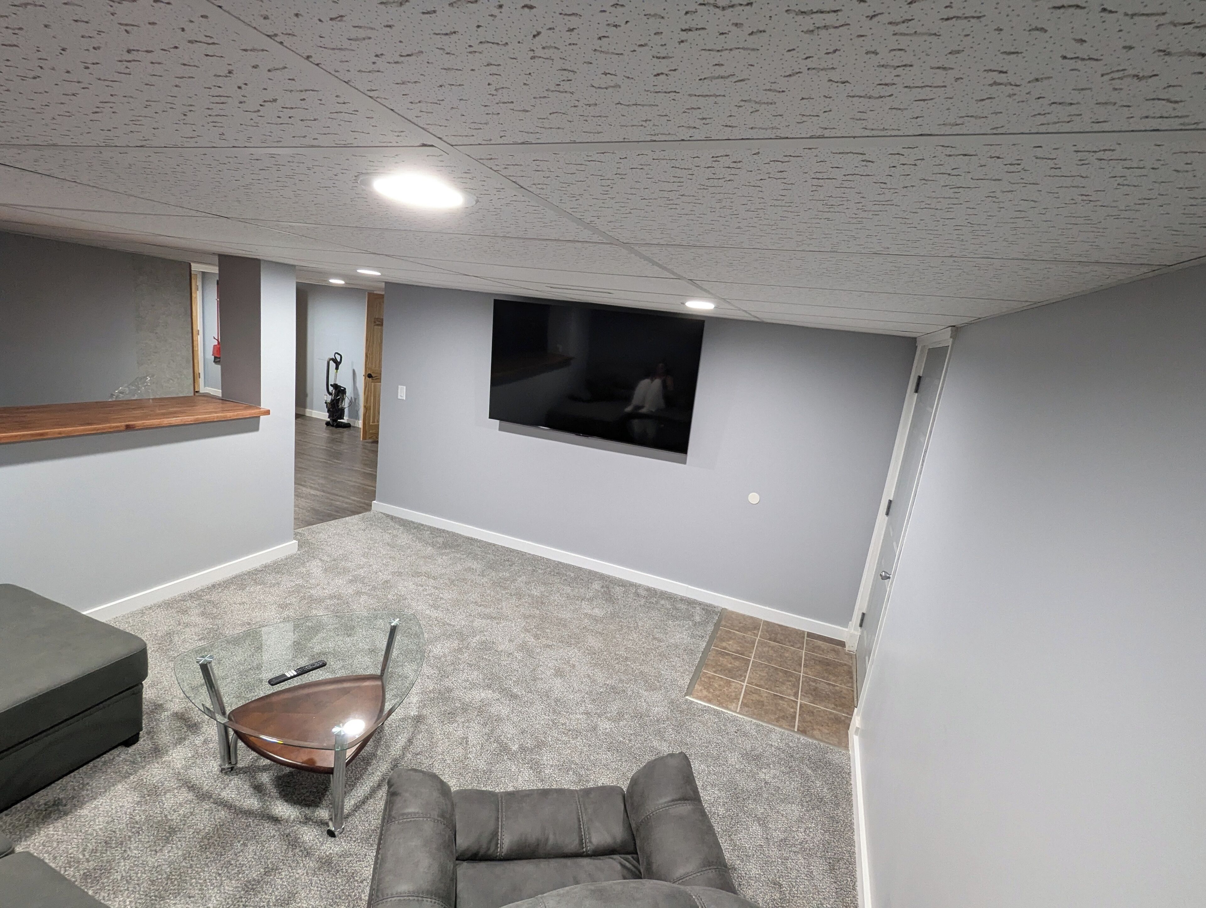 Un salón amplio con un sofá gris, una mesa de centro de vidrio y una alfombra gris.