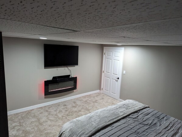 A bedroom with a bed, a TV mounted on the wall, and a door.