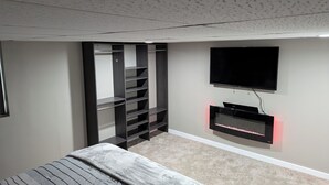 Une chambre à coucher avec un lit, un téléviseur fixé au mur et une armoire avec des étagères.