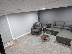 A living room with a gray sofa, a leather armchair, and a glass coffee table.
