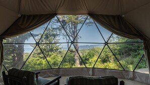 Une tente offrant une vue sur une forêt et un plan d’eau.