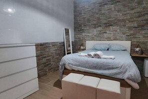 A bedroom with a bed, a white dresser, a mirror, and a brick-patterned wall. - Amazon Jacuzzi Relax in the Heart of the Harbor (El Puerto de Santa María)