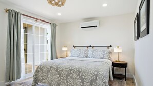 Een slaapkamer met een bed, twee bedlampen, een plafondventilator en een schuifdeur van glas.