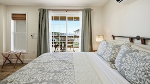 Een slaapkamer met een groot bed, een raam met gordijnen, een airconditioning en uitzicht op het exterieur.
