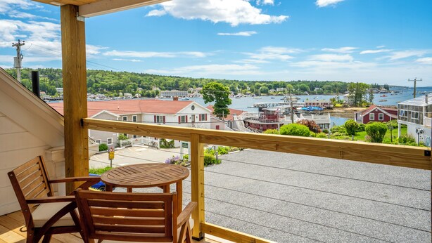 Un balcon en bois offrant une vue sur un port, avec des bateaux et des bâtiments.