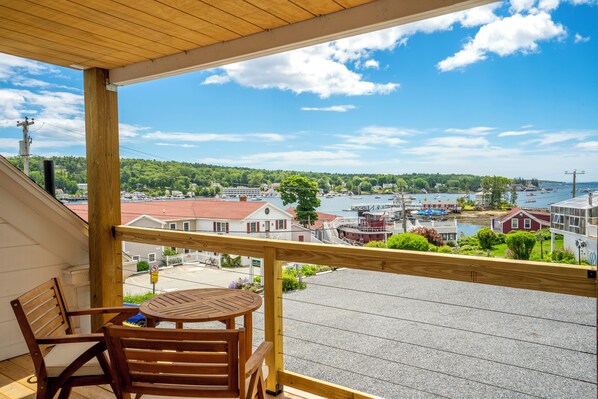 Un balcon en bois offrant une vue sur un port, avec des bateaux et des bâtiments.