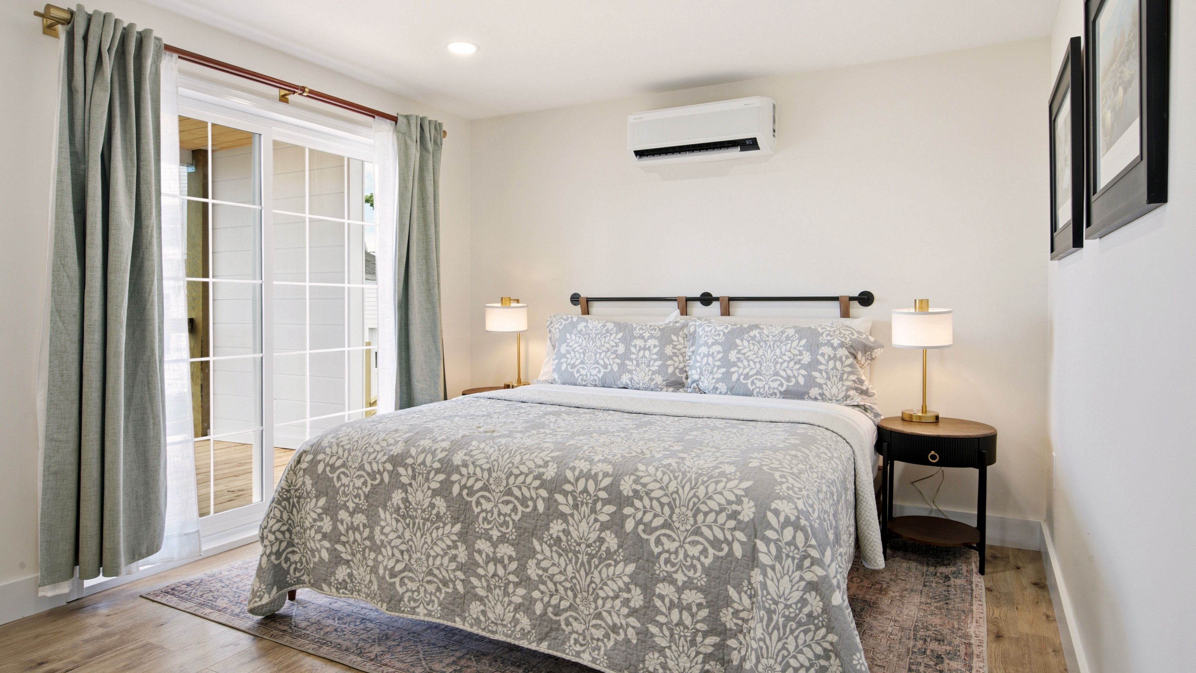 Ein Schlafzimmer mit einem Bett, zwei Nachttischlampen, einer Klimaanlage und einer Schiebetür.