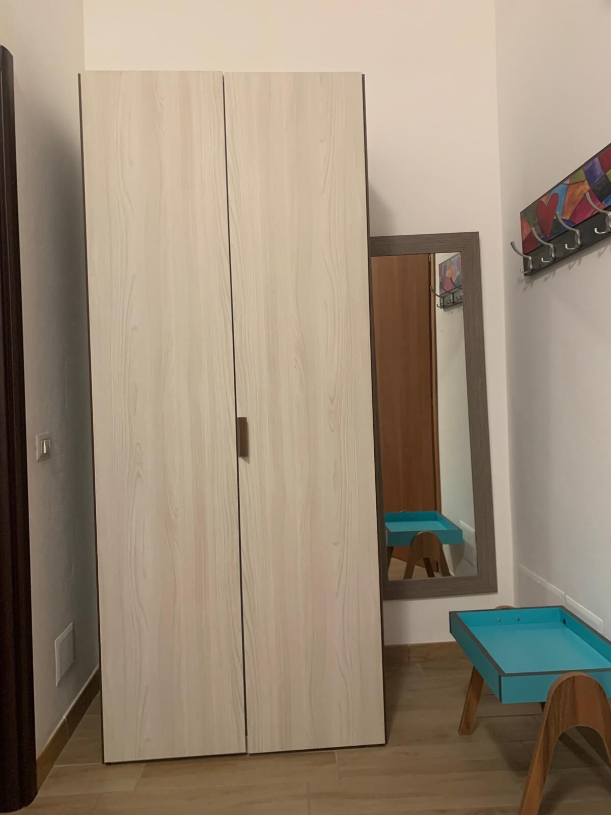 A room with a wardrobe, a mirror, and a small table.