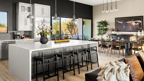 Una cucina moderna con un'isola centrale, sgabelli da bar e un'area pranzo con sedie.