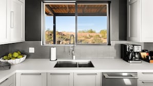 Una cucina moderna con un'ampia finestra, elettrodomestici in acciaio inox e vista sul paesaggio desertico.