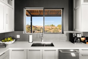 Eine moderne Küche mit einem großen Fenster, Edelstahlgeräten und Blick auf die Wüstenlandschaft.