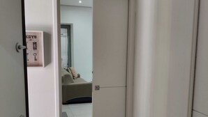 Huone, jossa on suljettu ovi, sänky ja pieni ikkuna, jossa on sälekaihtimet.