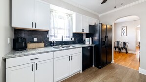 A modern kitchen with white cabinets, a black refrigerator, and a coffee maker. - 5BR Home Near Airport, Expo, Downtown Sleeps 12 (Louisville)