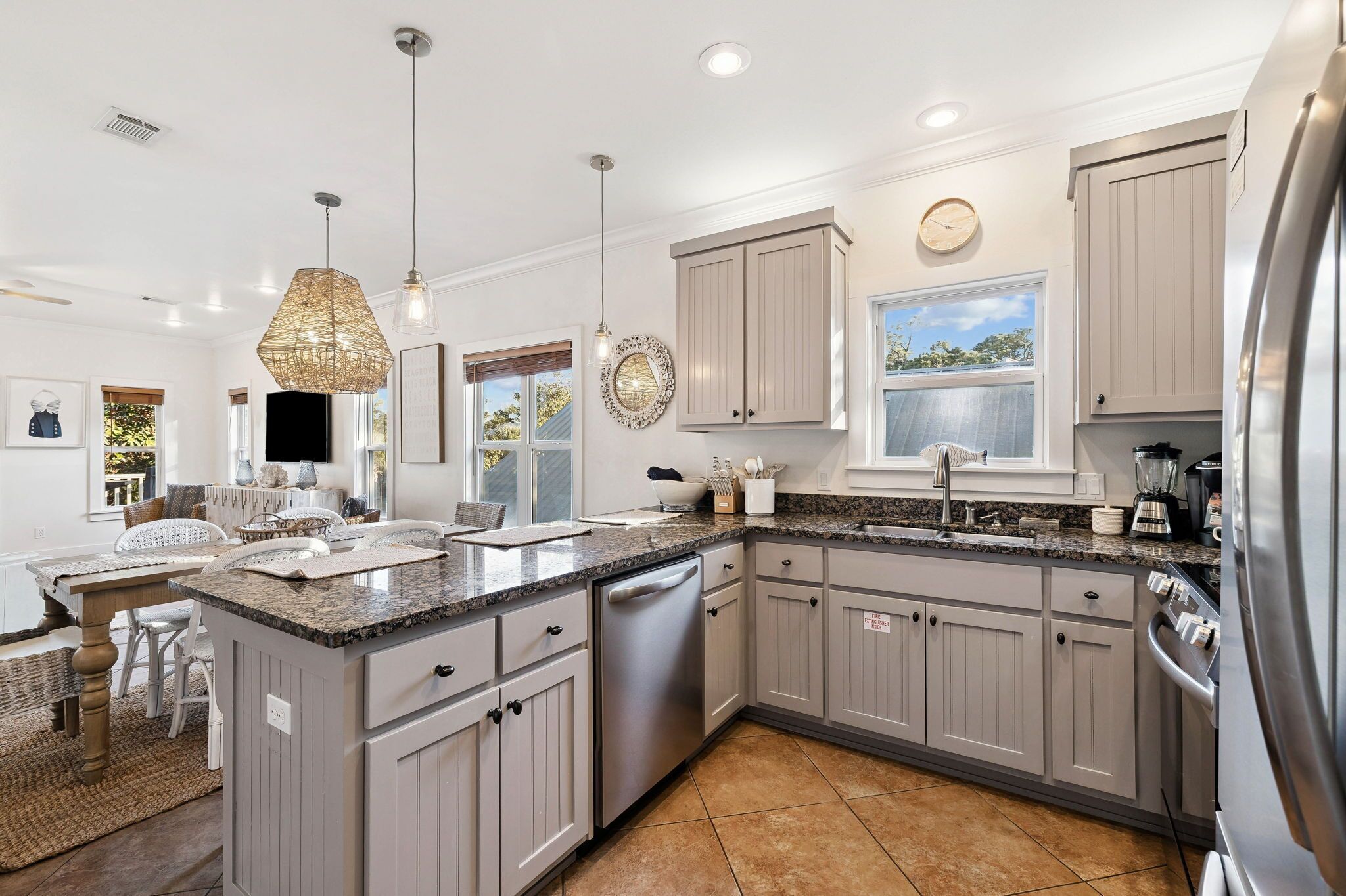 A modern kitchen with grey cabinets, stainless steel appliances, and a granite countertop.