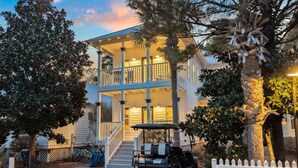 A two-story house with a balcony, a golf cart, and a white picket fence. - Pool Access | LSV | Dogs Welcome (Santa Rosa Beach)