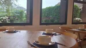 A dining area with round tables, chairs, and white cups on saucers. - LOGIS AUBERGE DES AULNETTES (Houlgate)