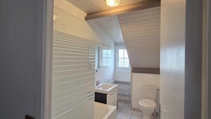 A narrow, single-bathroom with a sloped ceiling, a window, and a white toilet. - LOGIS AUBERGE DES AULNETTES (Houlgate)