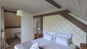 Ein Schlafzimmer mit Bett, Nachttisch, Lampe und einem Fenster mit Vorhängen.