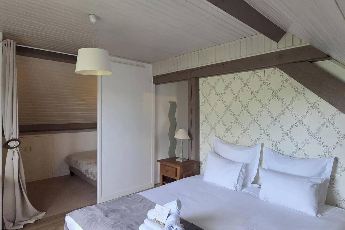 A bedroom with a bed, a nightstand, a lamp, and a window with curtains.
