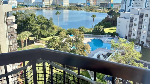 A view of a hotel with a pool, surrounded by greenery and a lake. - Ultimate Remodeled 2BR Condo at Enclave Suites (Orlando)