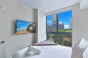 A hotel room with a bed, a window with a city view, a wall-mounted TV, and a door. - 2BR | Skyline Pool | Free Metromover Nearby (Miami)